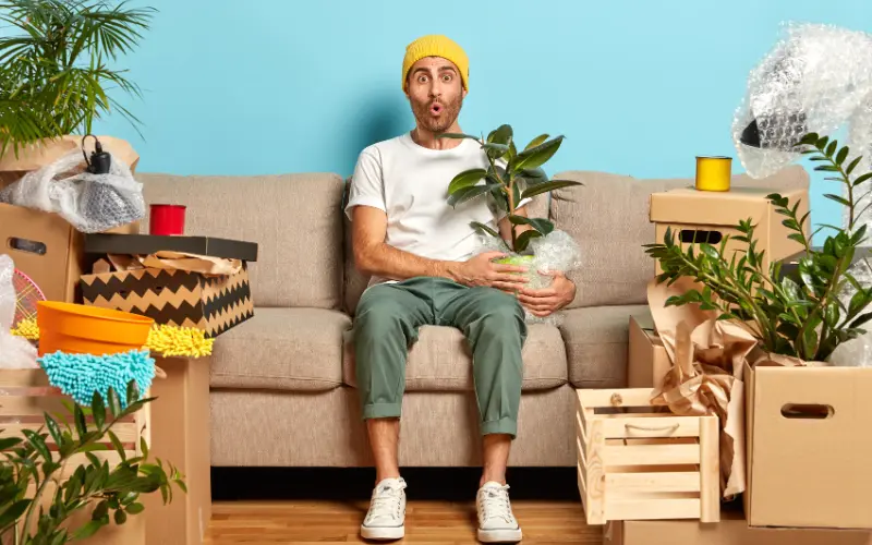 Homem jovem no sofá em meio às caixas de mudança